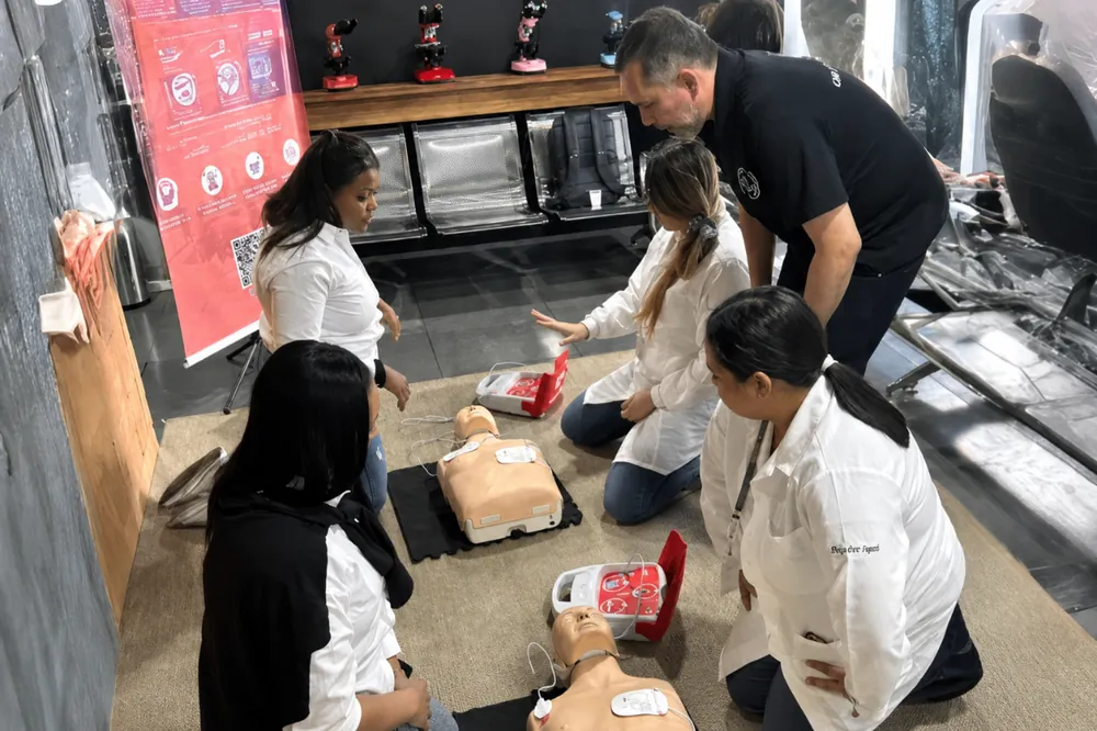 Turma de funcionários praticando reanimação cardiopulmonar durante treinamento presencial